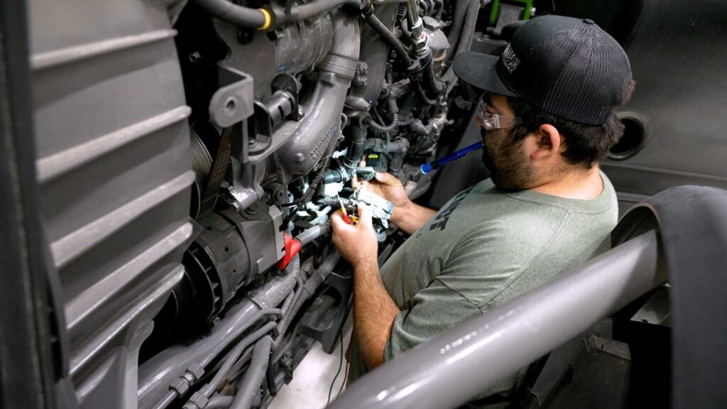 Cody performing diagnostics near the engine of a Fendt tractor