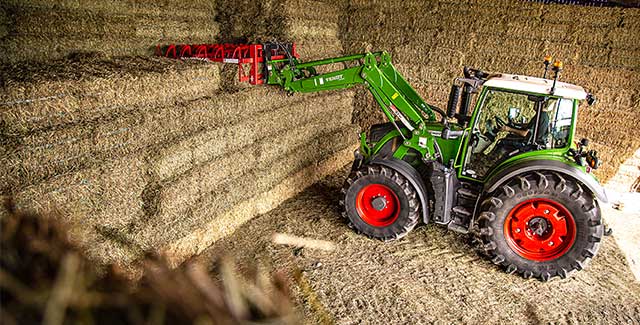 fendt 500 tractor with loader and bale hook picking bale off pile