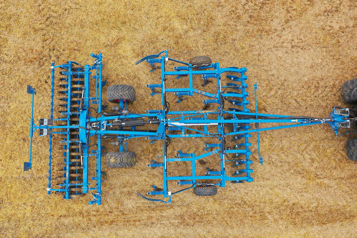 Top view of a Lemken Karat 10 semi-mounted cultivator working in a stubble field, showing heavy-duty frame, tines, and roller system for efficient soil cultivation.