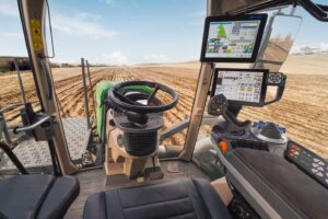 Interior view of the Fendt Rogator cab showcasing ergonomic controls, advanced touchscreen monitors, and a panoramic field view, designed for precision farming and operator comfort.