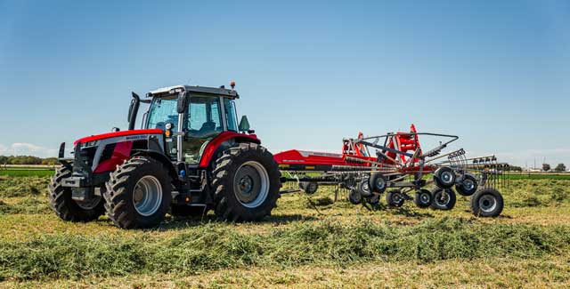 Massey Ferguson RK922 TRC-G2 rotary rake hitched to a tractor raking hay in southern Alberta, available at Hanlon Ag Centre farm equipment dealership.