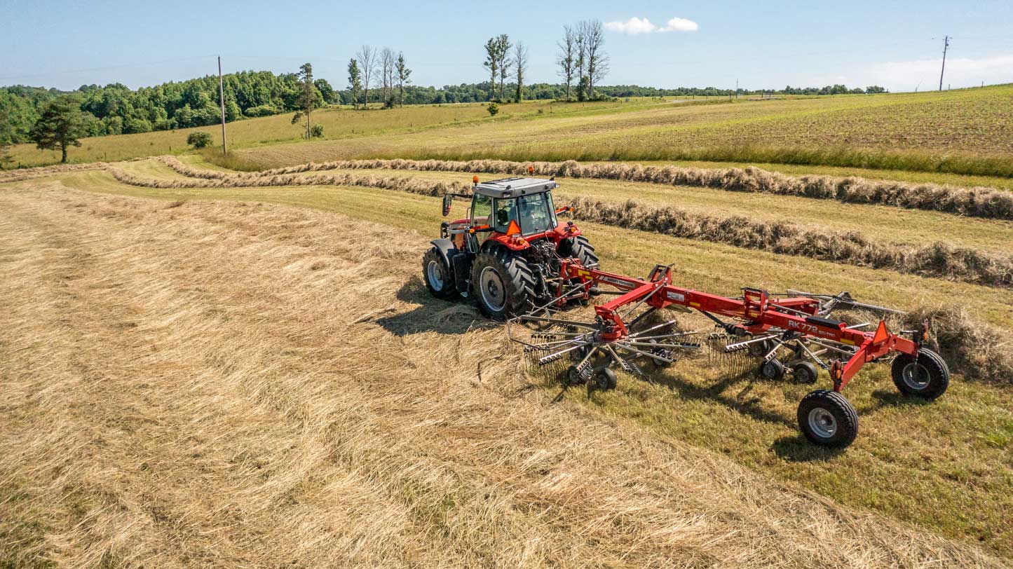 Massey Ferguson tractor with RK772 rotary rake working in a hay field near Hanlon Ag Centre, southern Alberta farm equipment dealer offering rakes, tractors, and hay tools for efficient haymaking.