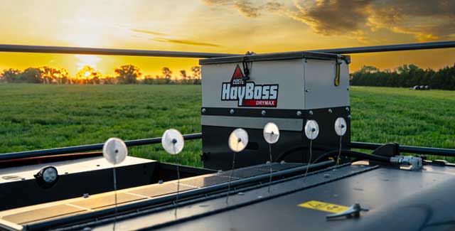 HayBoss DryMax hay preservative applicator mounted on a baler at sunrise in a southern Alberta hay field, Hanlon Ag Centre Lethbridge farm equipment dealership.