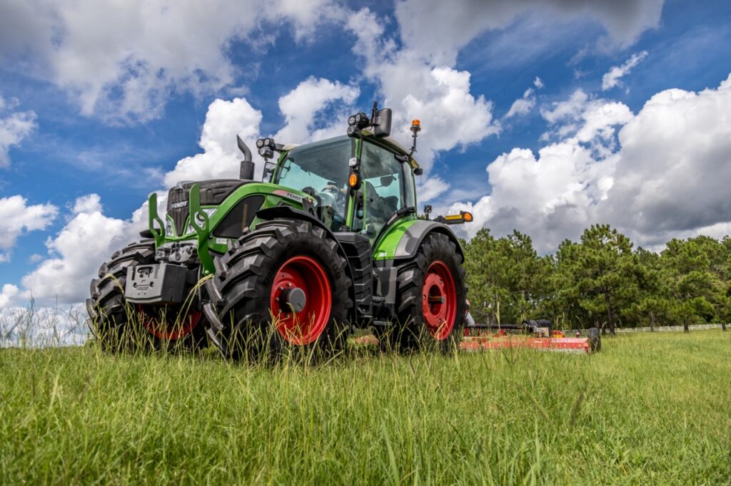 Fendt tractor operating in a grassy field under blue skies, highlighting a modern high-horsepower agricultural tractor built for haying, field work, and mixed farming operations in southern Alberta, available at Hanlon Ag Centre.