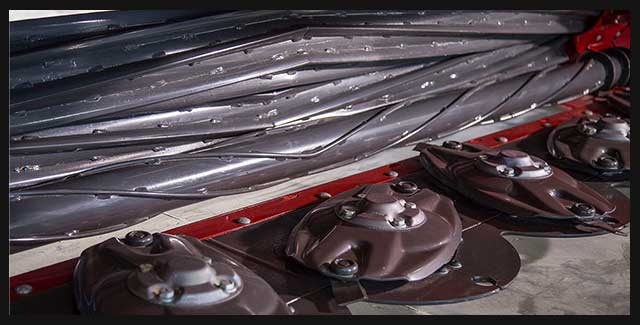 Close-up of mower conditioner cutting discs and rollers on hay and forage equipment with parts supplied and serviced by Hanlon Ag Centre in southern Alberta. Demonstrating AGCO parts available at Hanlon Ag Centre.