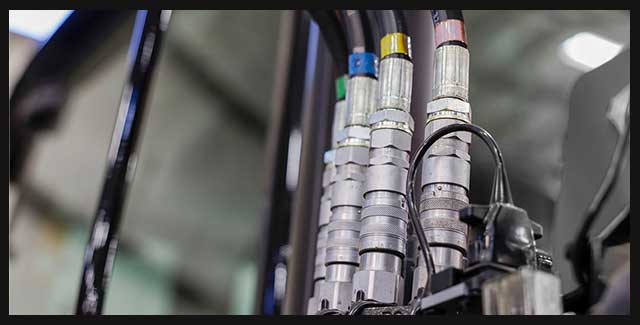 Close-up of colour-coded hydraulic hose couplers and fittings on modern farm equipment, highlighting precision hydraulics and reliable connections available at Hanlon Ag Centre in southern Alberta for Prairie agricultural operations. Demonstrating AGCO parts available at Hanlon Ag Centre.